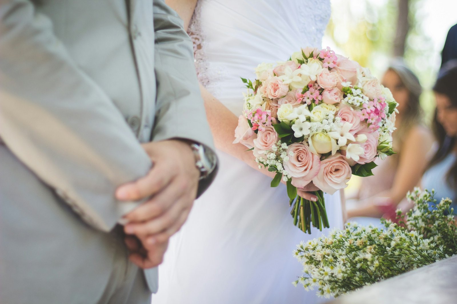 Bouquet of flowers held against a grey wedding suit